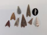 six different types of arrowheads and a coin on a white surface