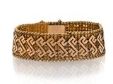 gros plan d'un bracelet en or sur une surface blanche