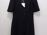 the black dress is hanging on a hanger against a white wall