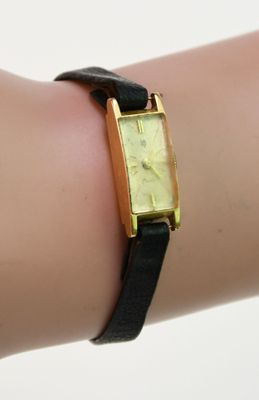 le poignet d'une femme, sur lequel est posée une montre en or