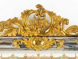 a gold and blue clock on a shelf with gold decorations