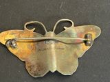 a metal butterfly brooch with a pin on it