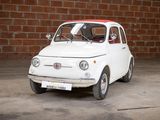 a small white car that is parked in front of a brick wall