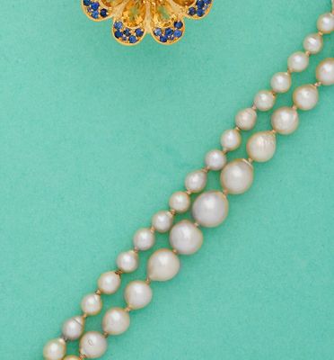un gros plan sur un collier orné de perles et d'une broche en forme de fleur
