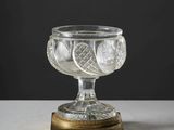 un bol en verre avec un socle doré posé sur une table