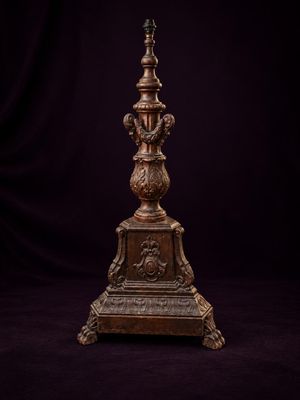 une horloge ancienne en bronze posée sur un socle, sur fond noir