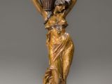 une statue antique en bronze représentant une femme portant un vase sur la tête
