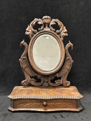 un miroir ancien en bois posé sur un pied, sur fond noir