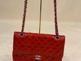 a red chanel bag on a stand on a white surface