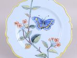 une assiette bleue et jaune sur laquelle est représenté un papillon