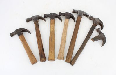 six old hammers are lined up on a white surface