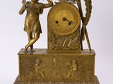une horloge ancienne en laiton ornée d'une statue représentant une femme tenant un bâton