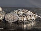 a silver bracelet that has a silver button on it