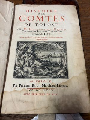un vieux livre posé sur une table en bois, à côté d'une paire de ciseaux