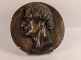 une image représentant une plaque en bronze représentant la tête d'un homme