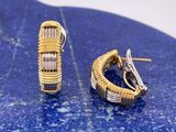 une paire de boucles d'oreilles créoles en or et diamants posées sur une plaque de marbre bleu
