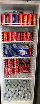 un réfrigérateur rempli de canettes de soda et de canettes de soda