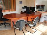 une table avec des chaises et un ordinateur posés dessus, dans une pièce