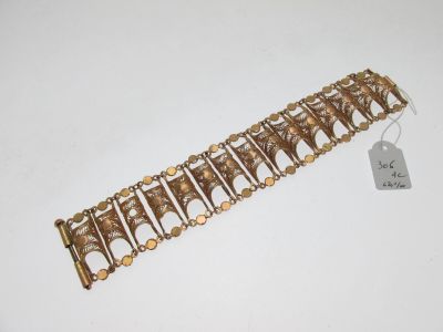 a close up of a gold bracelet on a white surface
