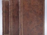 three brown leather books sitting on a white surface