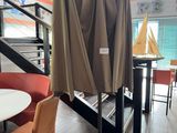 tables and chairs with umbrellas on them in a room with a staircase