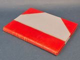 un vieux livre rouge et blanc posé sur une table bleue