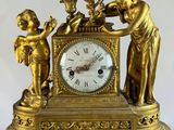 a gold clock with a statue of angels on top of it