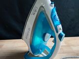 a blue and white steam iron on a wooden table
