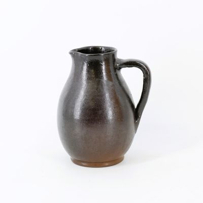 un pichet marron posé sur une surface blanche