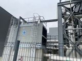 a large metal structure behind a fence and a building