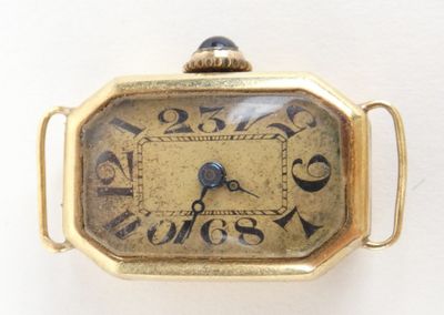 une petite montre en or dont le cadran est orné de chiffres romains
