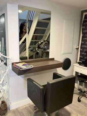 une photo d'un salon de coiffure avec un miroir accroché au mur