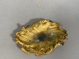 a gold flower brooch on a white surface