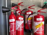 several fire extinguisors are lined up against a brick wall