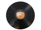 a black vinyl record with an orange label sitting on a white surface