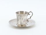 an antique silver cup and saucer on a saucer on a white background
