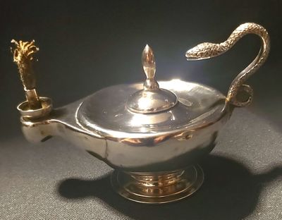 a silver teapot with a snake handle on a table