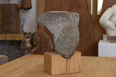 une sculpture en pierre posée sur un bloc de bois, elle-même posé sur une table