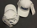 une paire de casquettes de baseball blanches portant l'inscription « France », posées sur une table