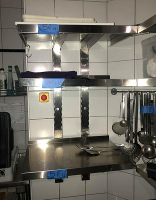 un plan de travail en acier inoxydable sur lequel sont posés des casseroles et des poêles, dans une cuisine professionnelle