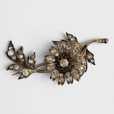 un gros plan d'une broche en forme de fleur posée sur une surface blanche