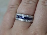 a woman ' s hand holding a diamond and sapphire ring