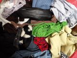 a pile of clothes and a cat laying on top of it