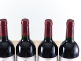 three bottles of red wine are lined up on a wooden tray