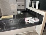 a black counter top in a kitchen with a sink and a mirror