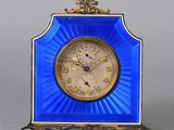 une petite horloge bleue avec un cadre doré posée sur une table