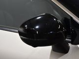 a side view mirror on a white car with a black handle