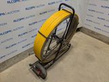 a yellow hose on a cart in front of a wall