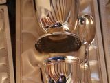 three silver cups and spoons in a box on a table