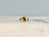 une image représentant une bague en or sertie d'une pierre bleue, posée sur une surface en marbre